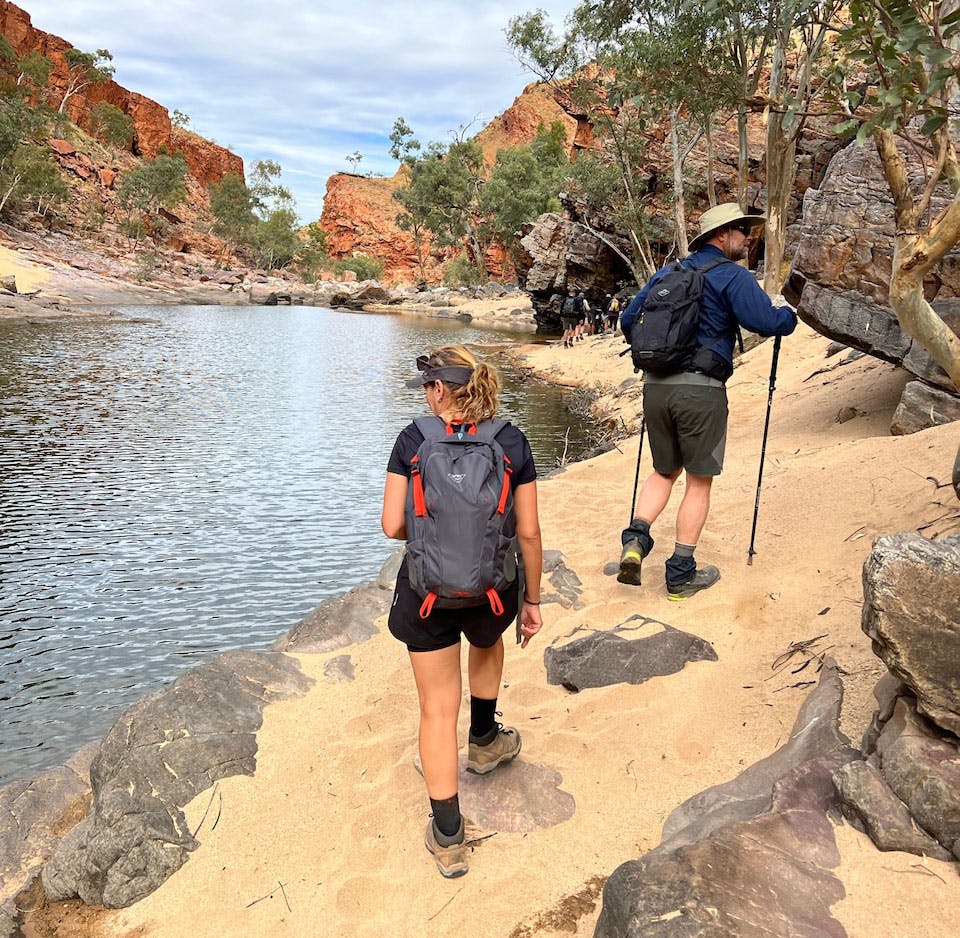 Group hiking along trail next to water - Executive retreats on the Larapinta Trail