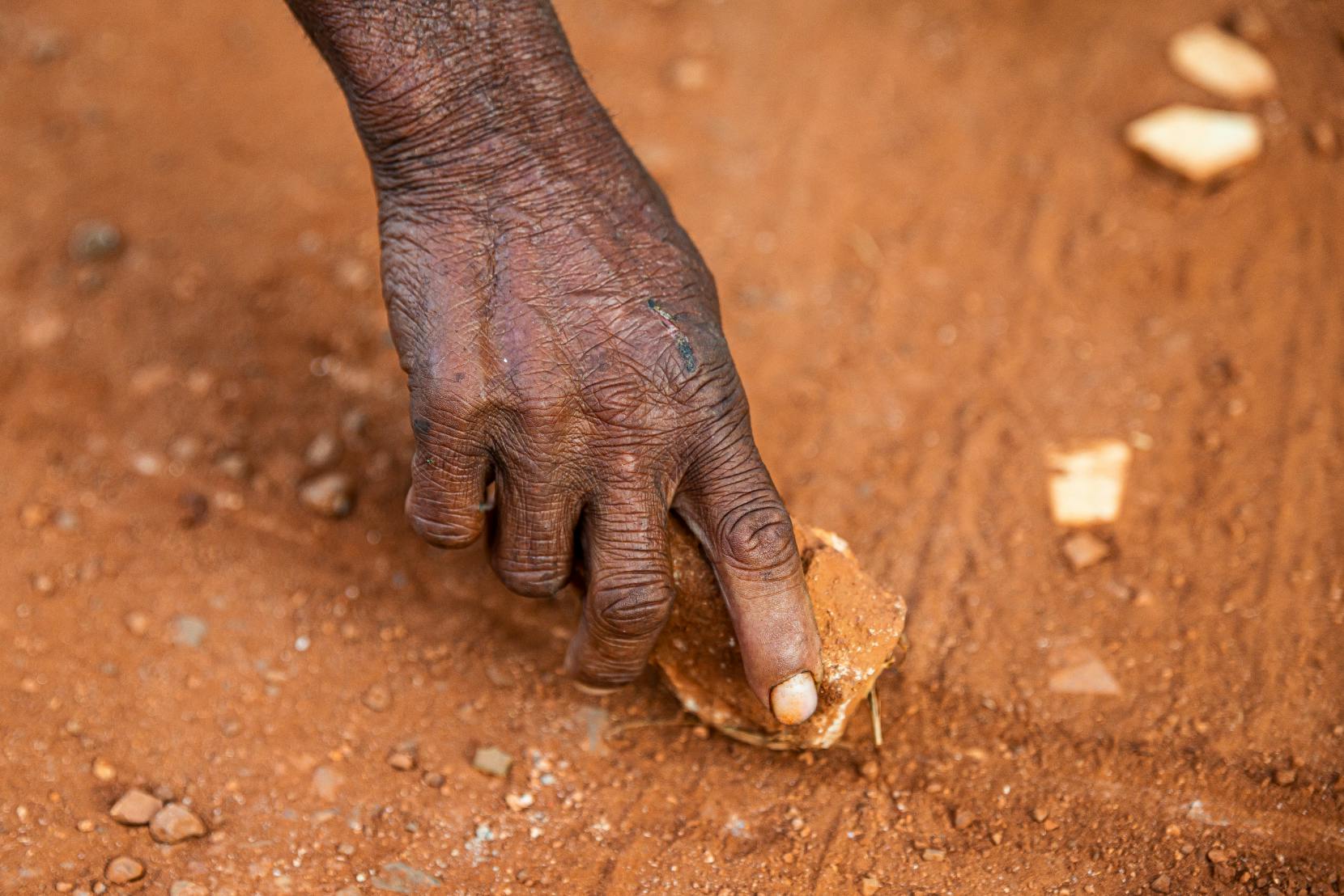 First Nations hand touching red dirt - Explore first-hand experience of First Nations people