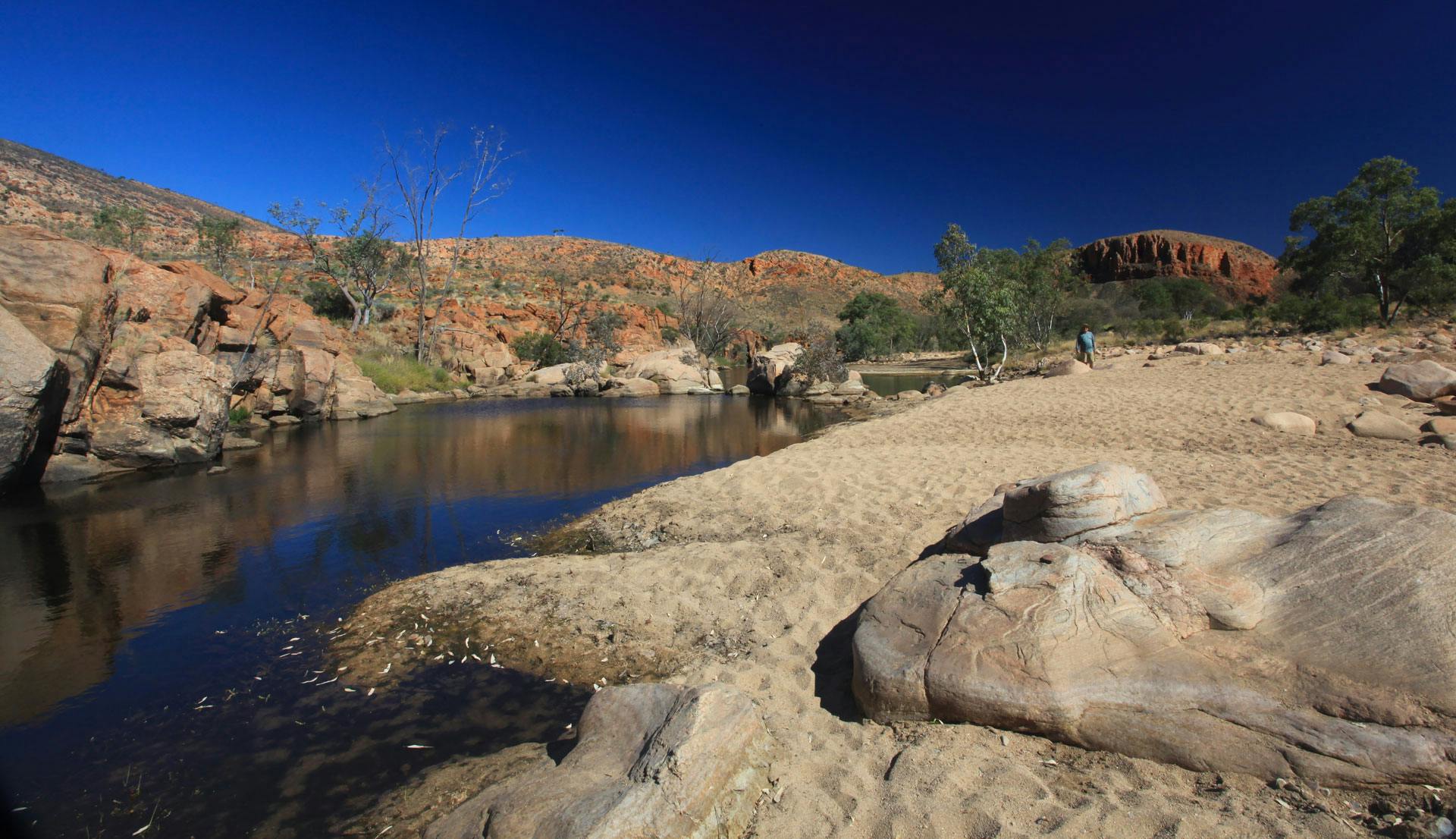 Rocks and sand next to water - experience unique personal development in the heart of Australia