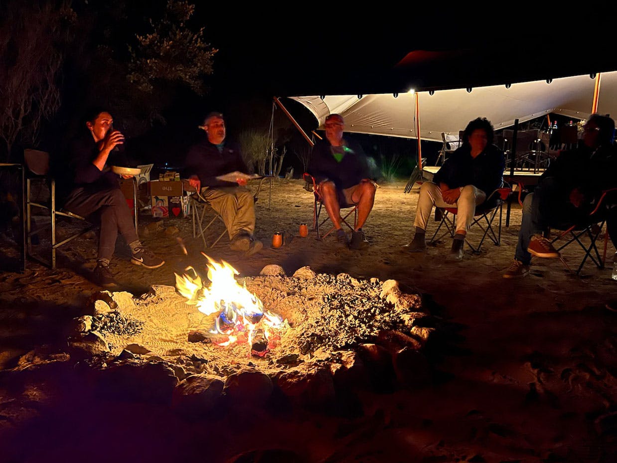 Group of people around a campfire - gain a deeper sense of meaning on a retreat in the Larapinta region